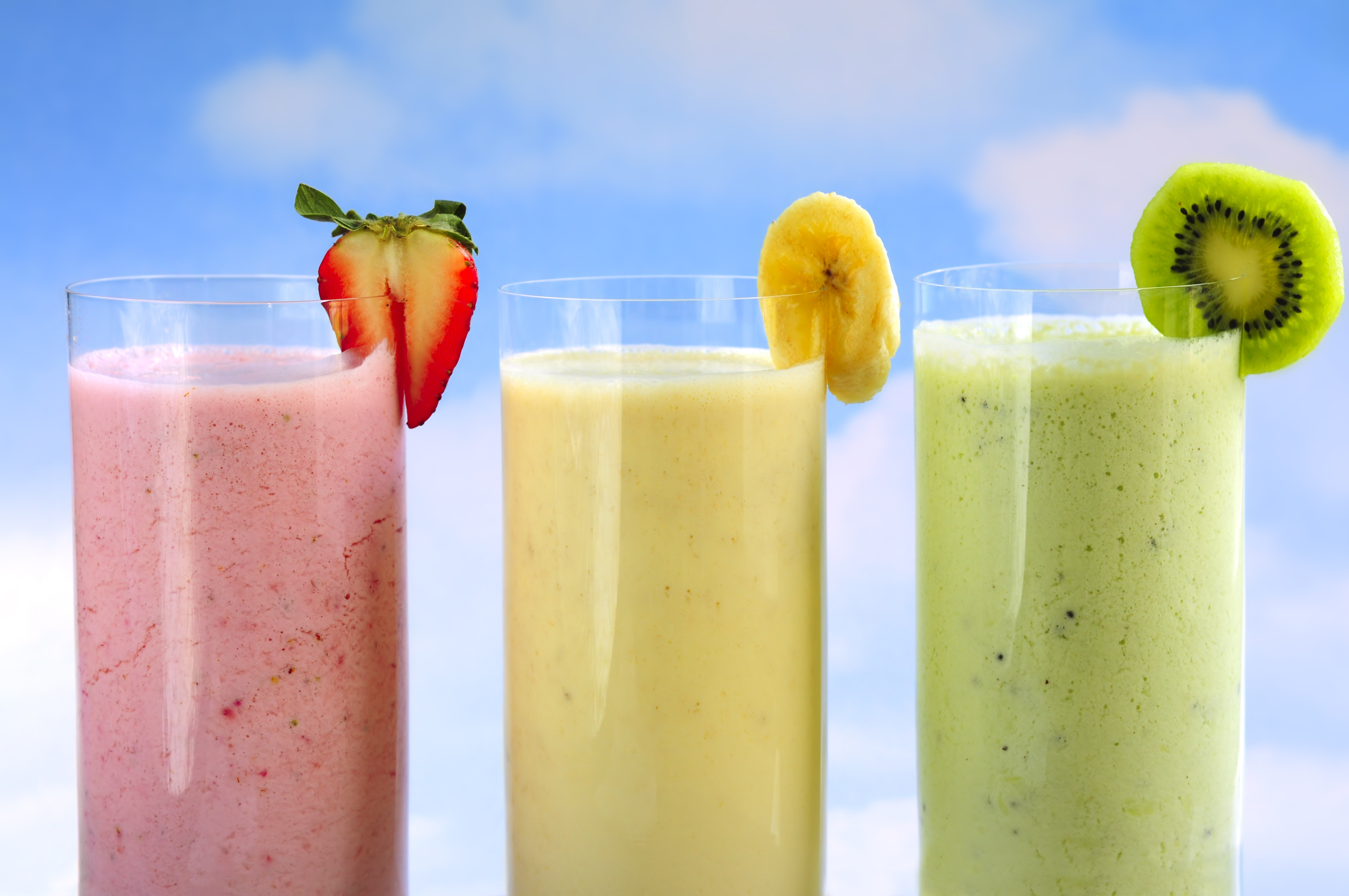 Assorted fruit and berry smoothies on blue sky background