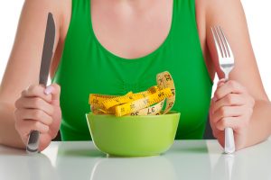 Concept image of a woman on a diet, eating a measuring tape, isolated on white