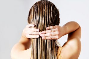 59416037 - blond woman applying hair conditioner. isolated on white.